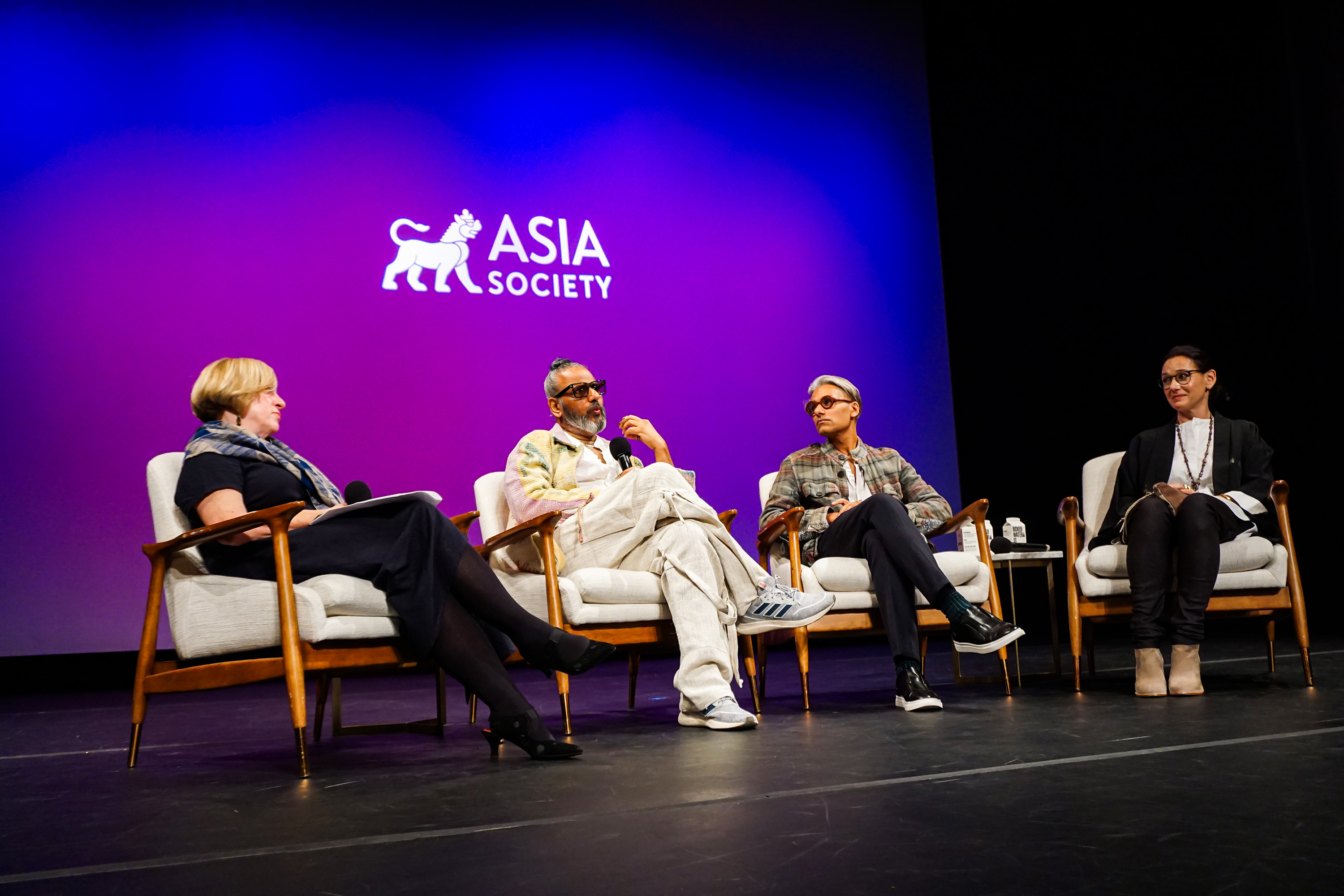 Ajay Shrivastav, Carmen Artigas Sandy Dalal, Rachel Cooper in chairs on stage with a purple background with Asia Society logo