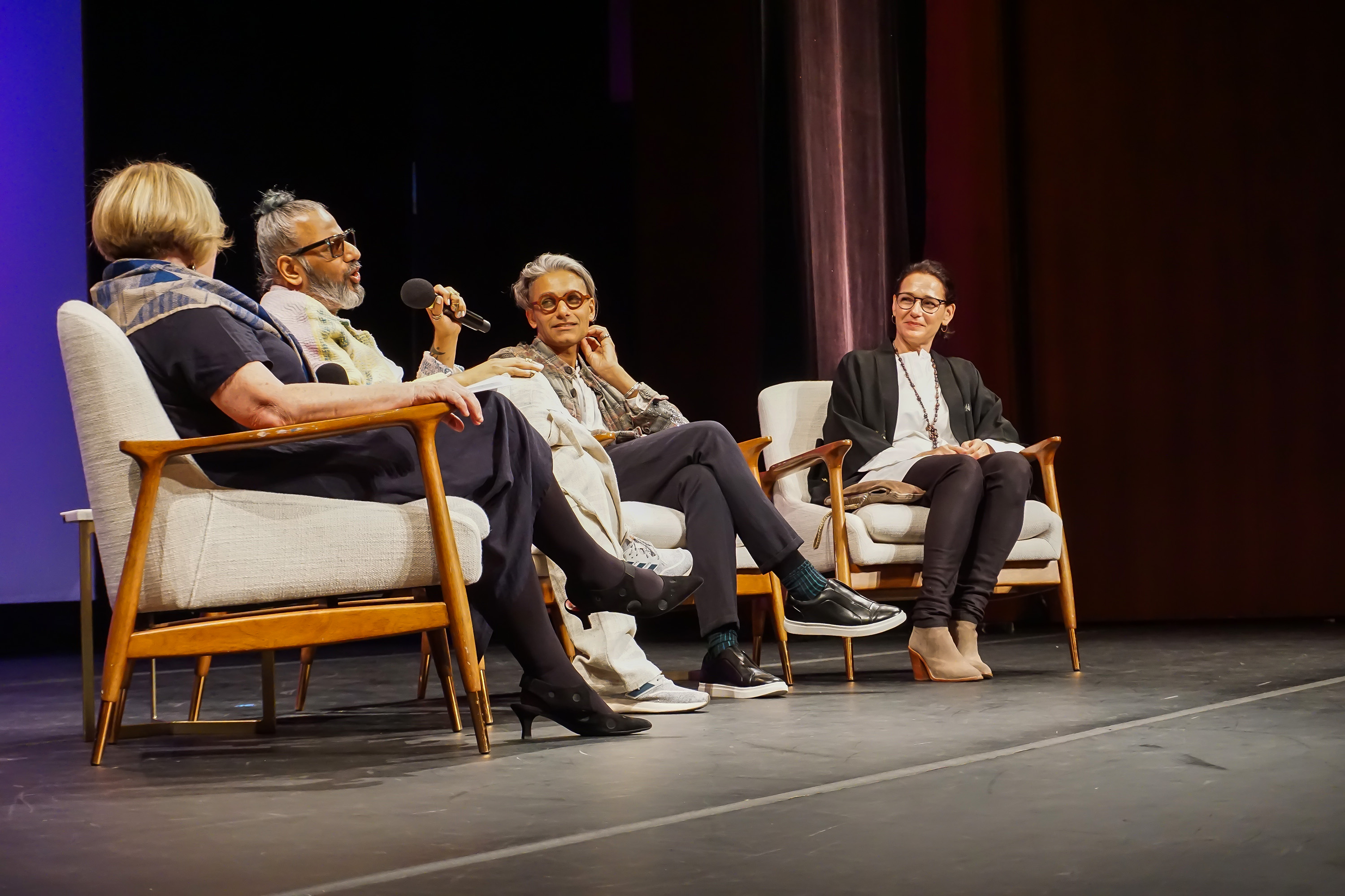 Ajay Shrivastav speaking in microphone with Carmen Artigas Sandy Dalal, Rachel Cooper sitting on stage together