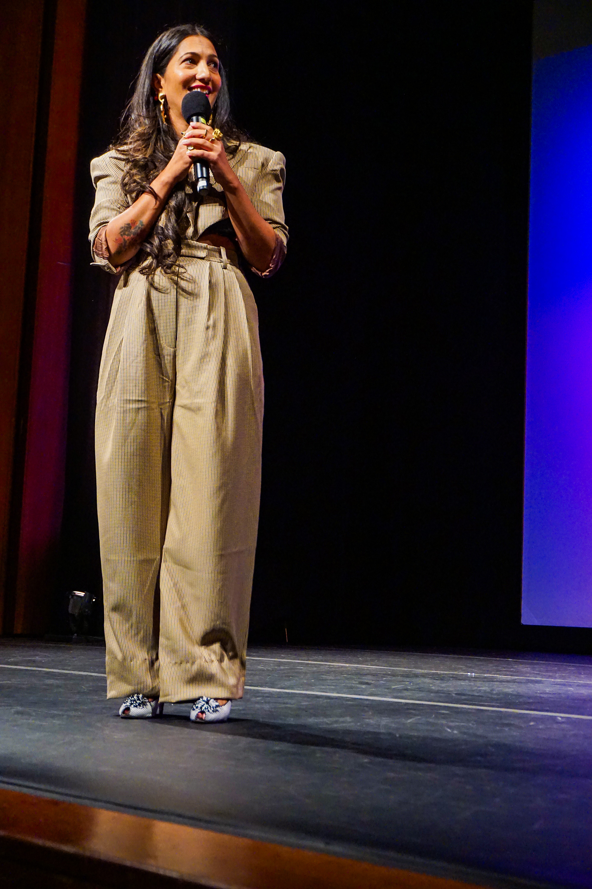 Poonam Thimmaiah on stage holding the microphone look to the side of the stage