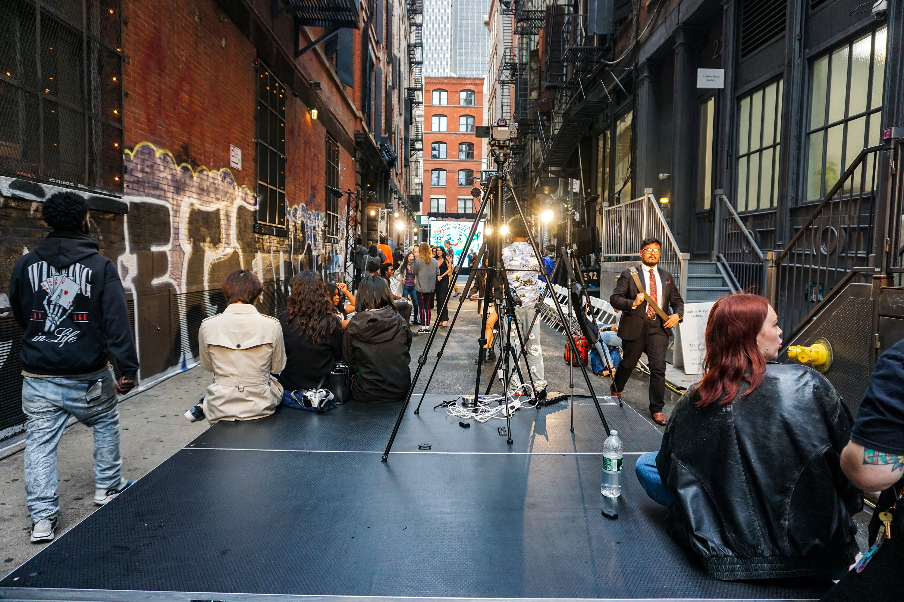 An outdoor stage with people sitting on it and others setting up for a fashion show at Walker Hotel New York