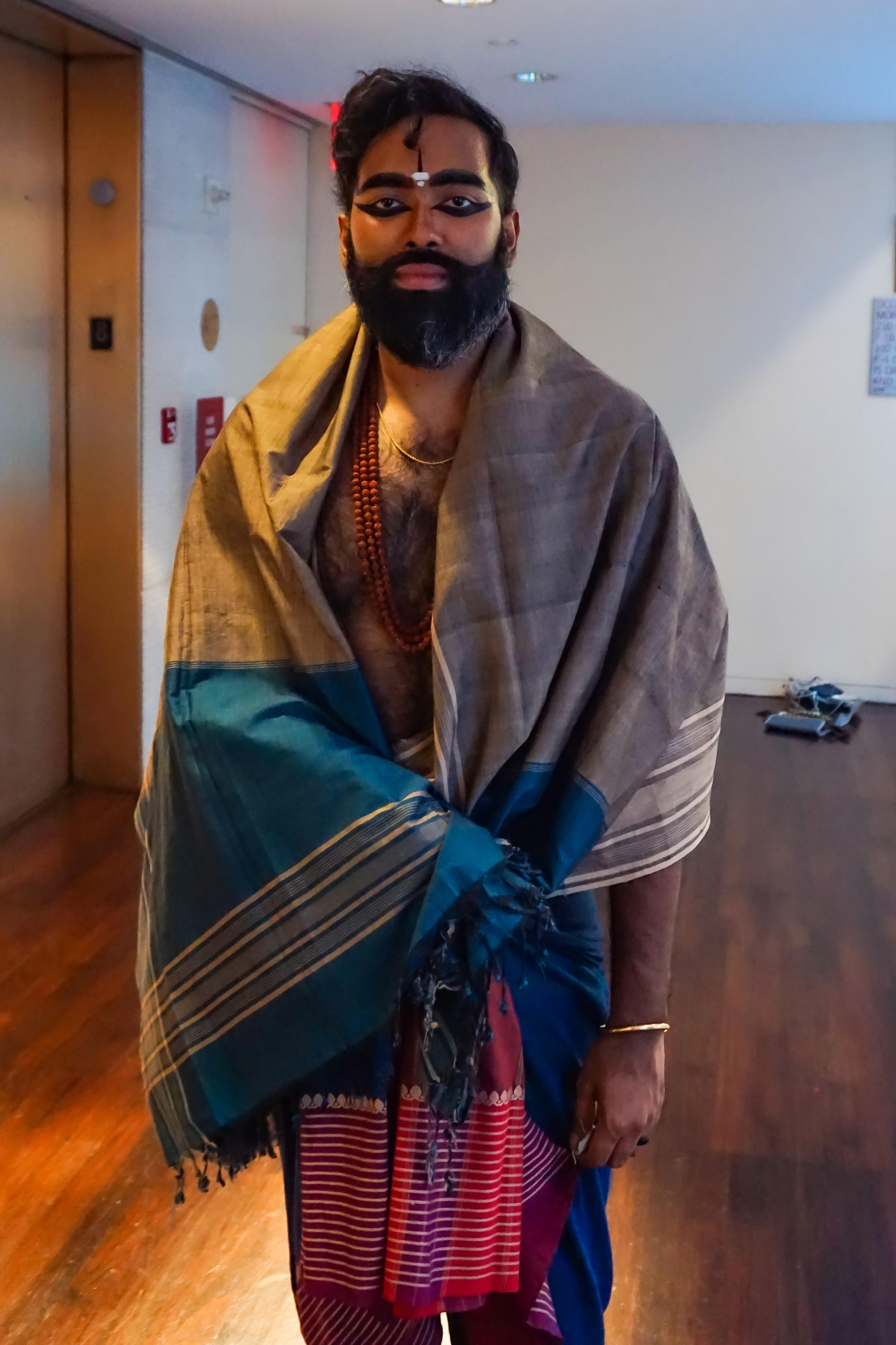 Jeeno Joseph with face make up on standing with a blanket over his body in preparation for his performance