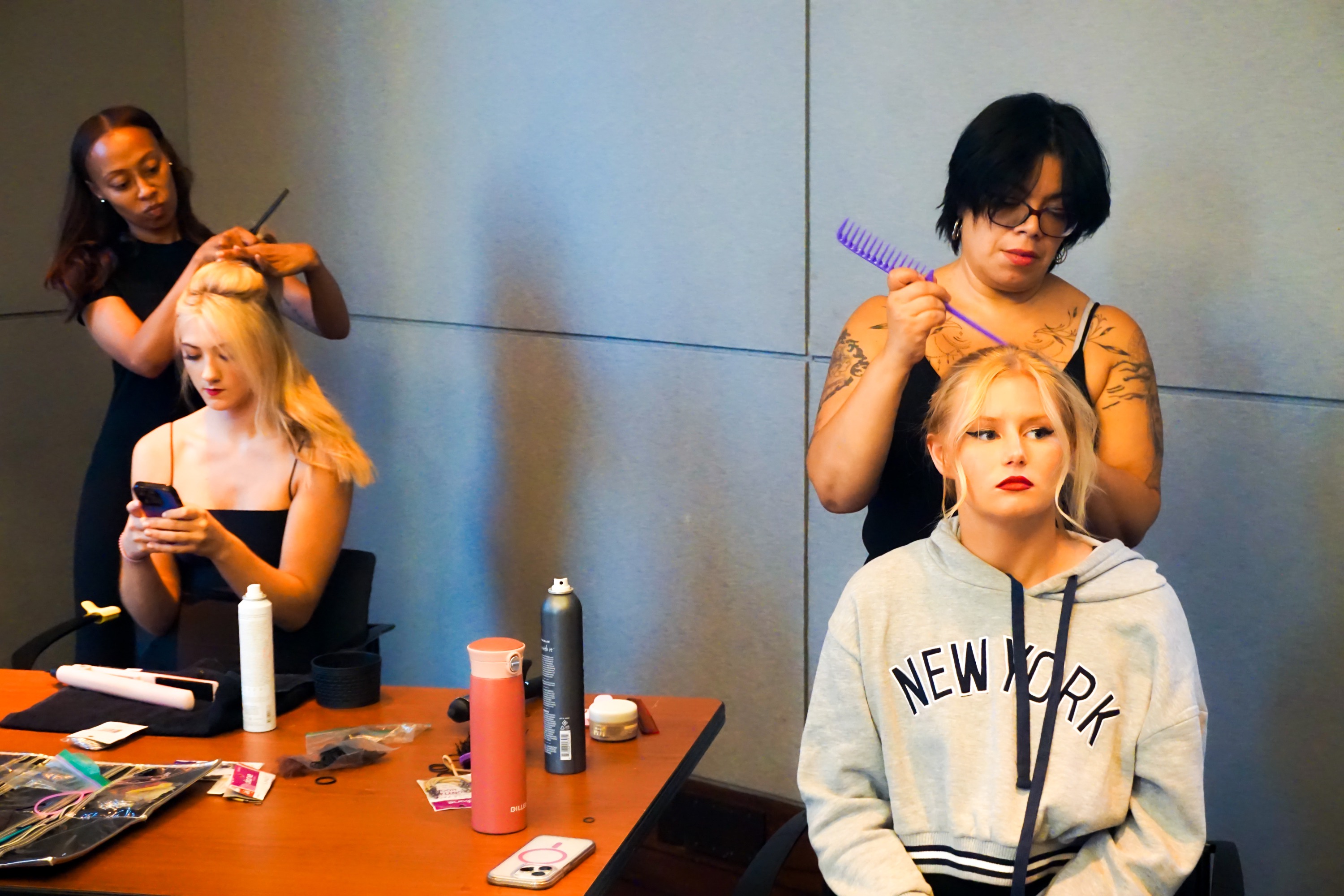 Two hairstylists working on their female models backstage