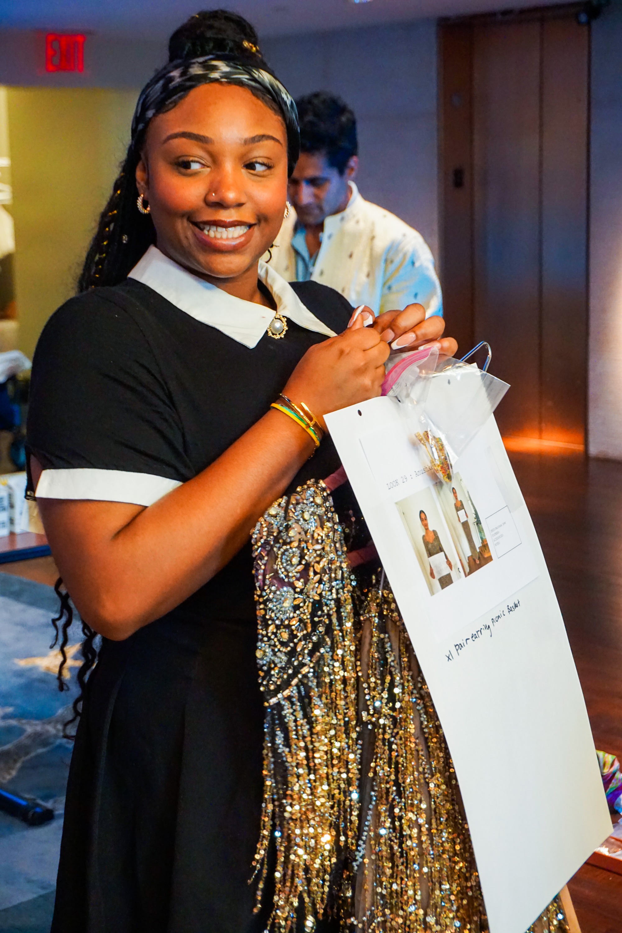 Backstage female staff member holding a dress in preparation for a model to wear it for the fashion show