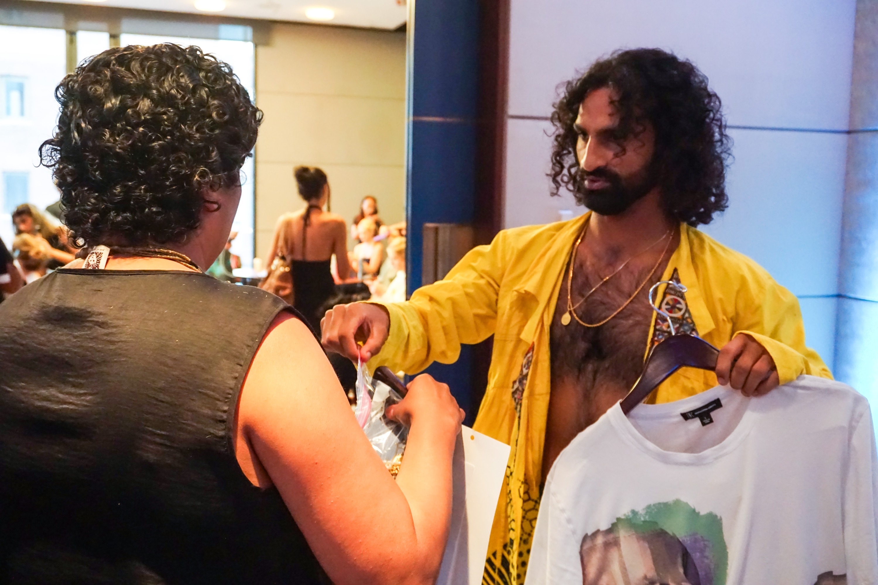 A model accepting fashion clothing from staff backstage