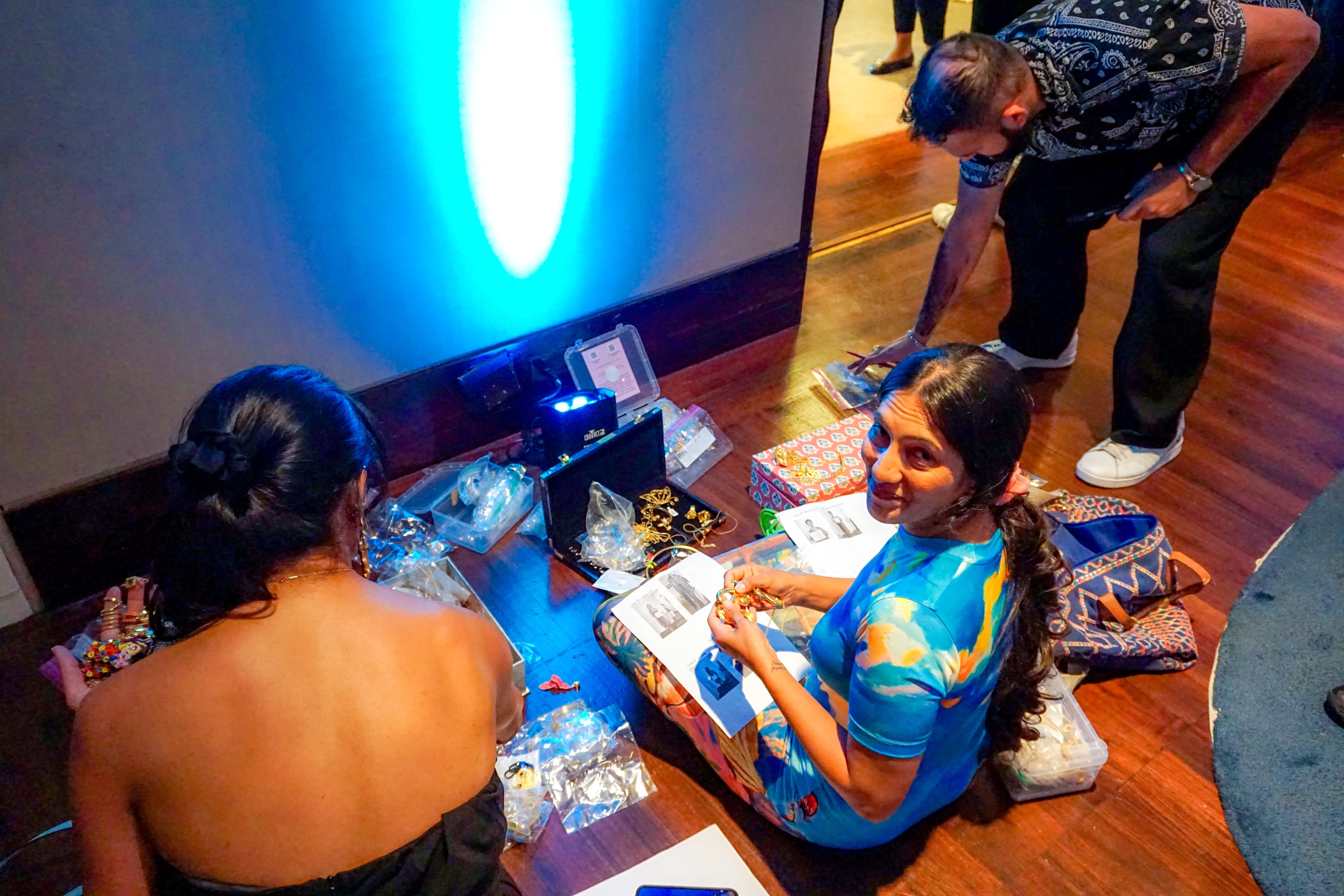 People sitting on a floor arranging jewelry in preparation for the fashion show at Asia Society NYC