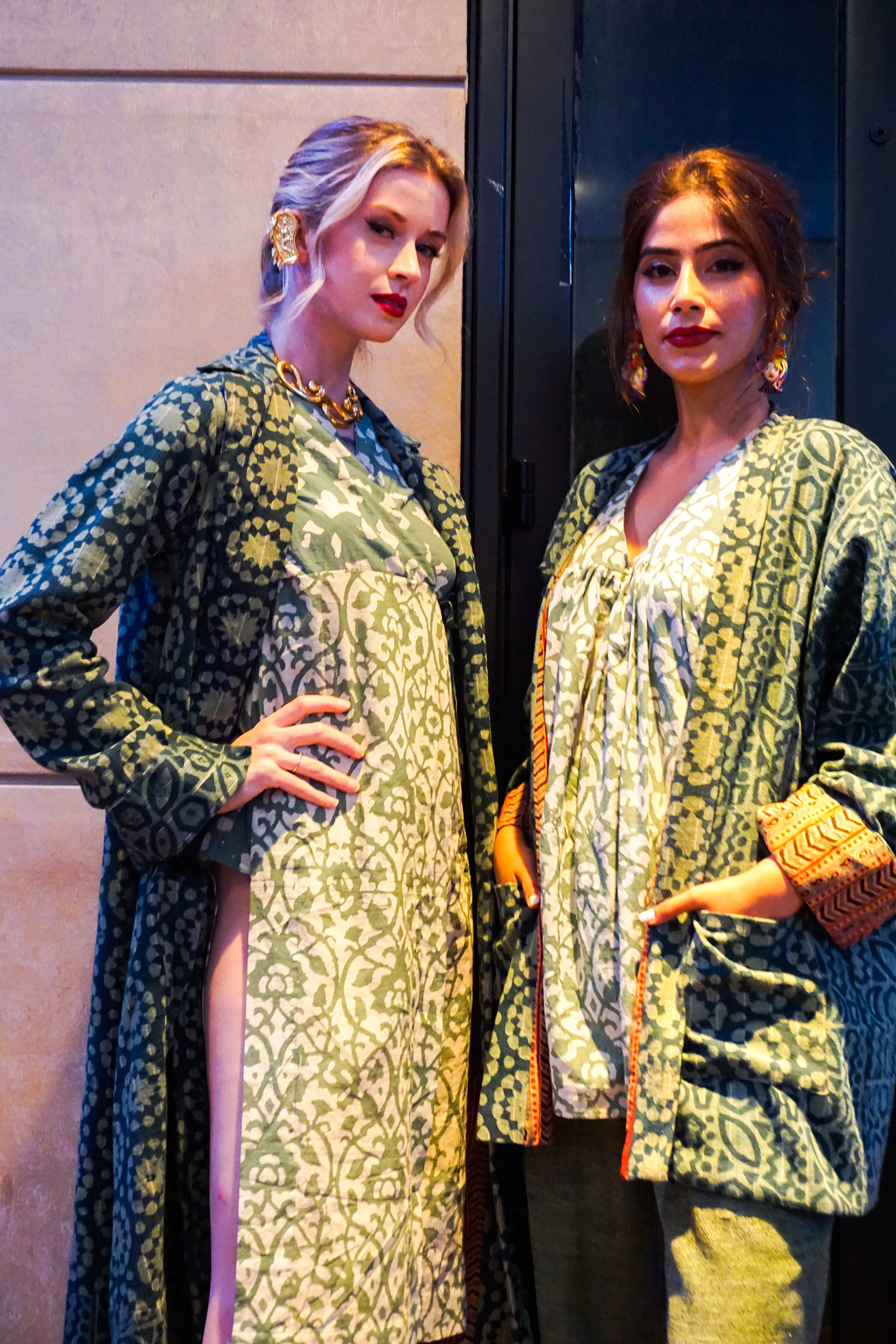 Two models wearing green Indian style clothing facing the camera