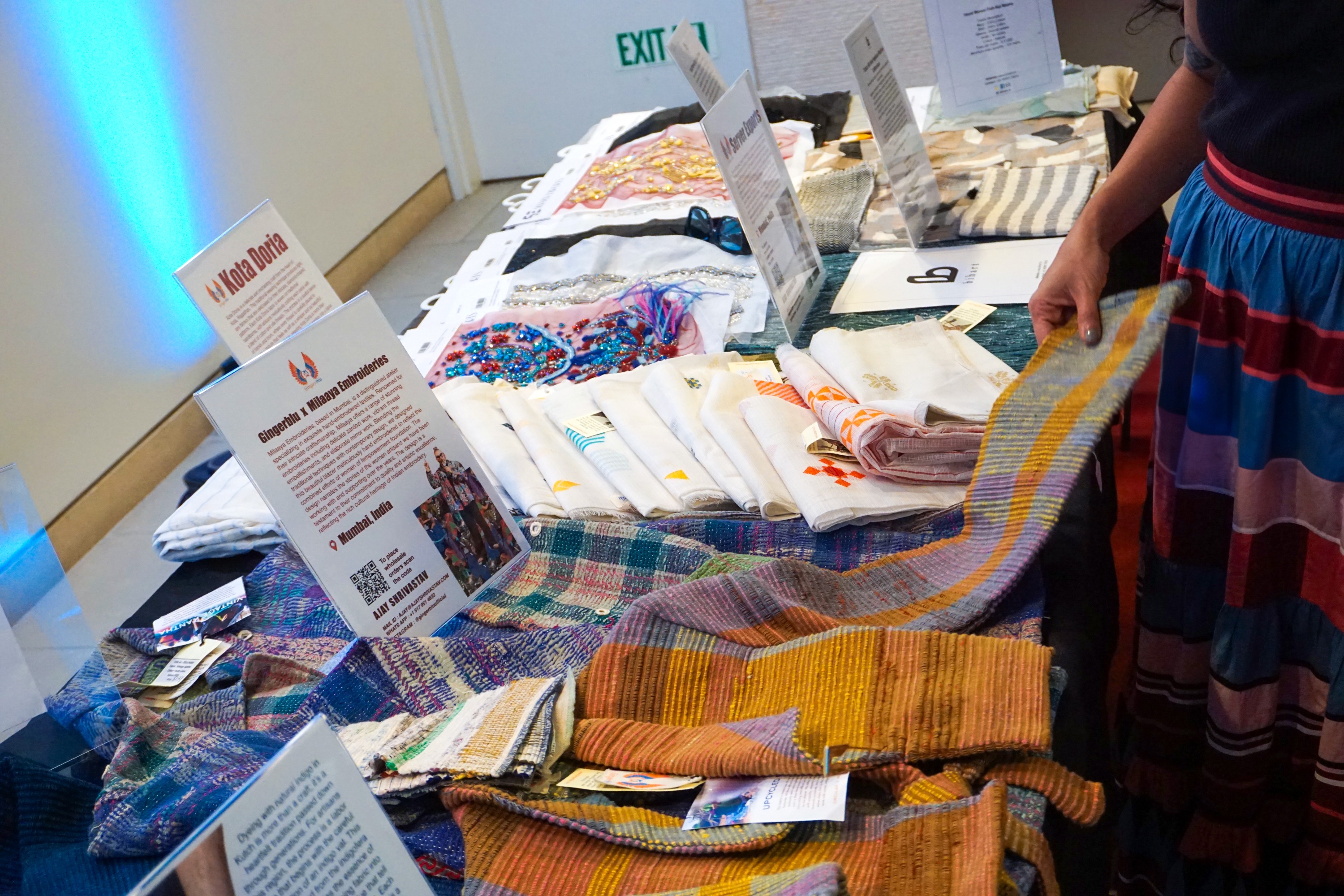 Ajay Shrivastav's table of textiles laid out being examined by a woman