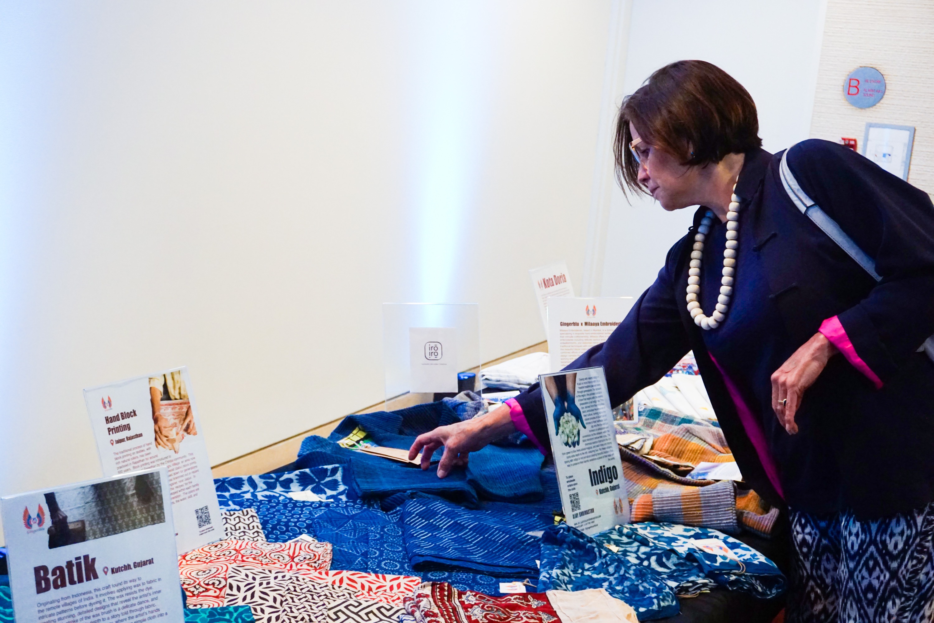 A woman reaching out to examine textiles on a desk