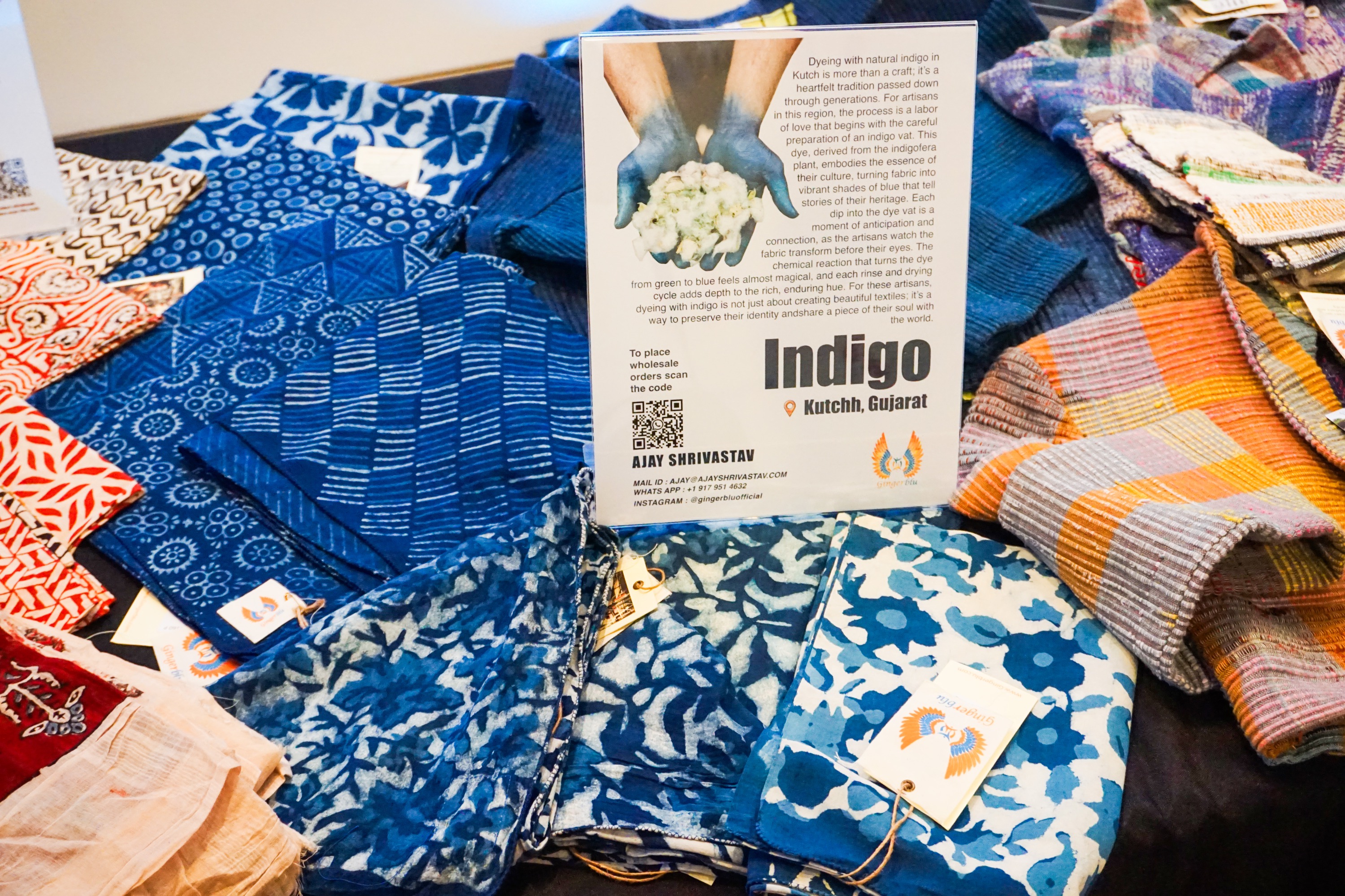 close up of blue patterned textiles laid out on a table with a sign indicating its style and materials