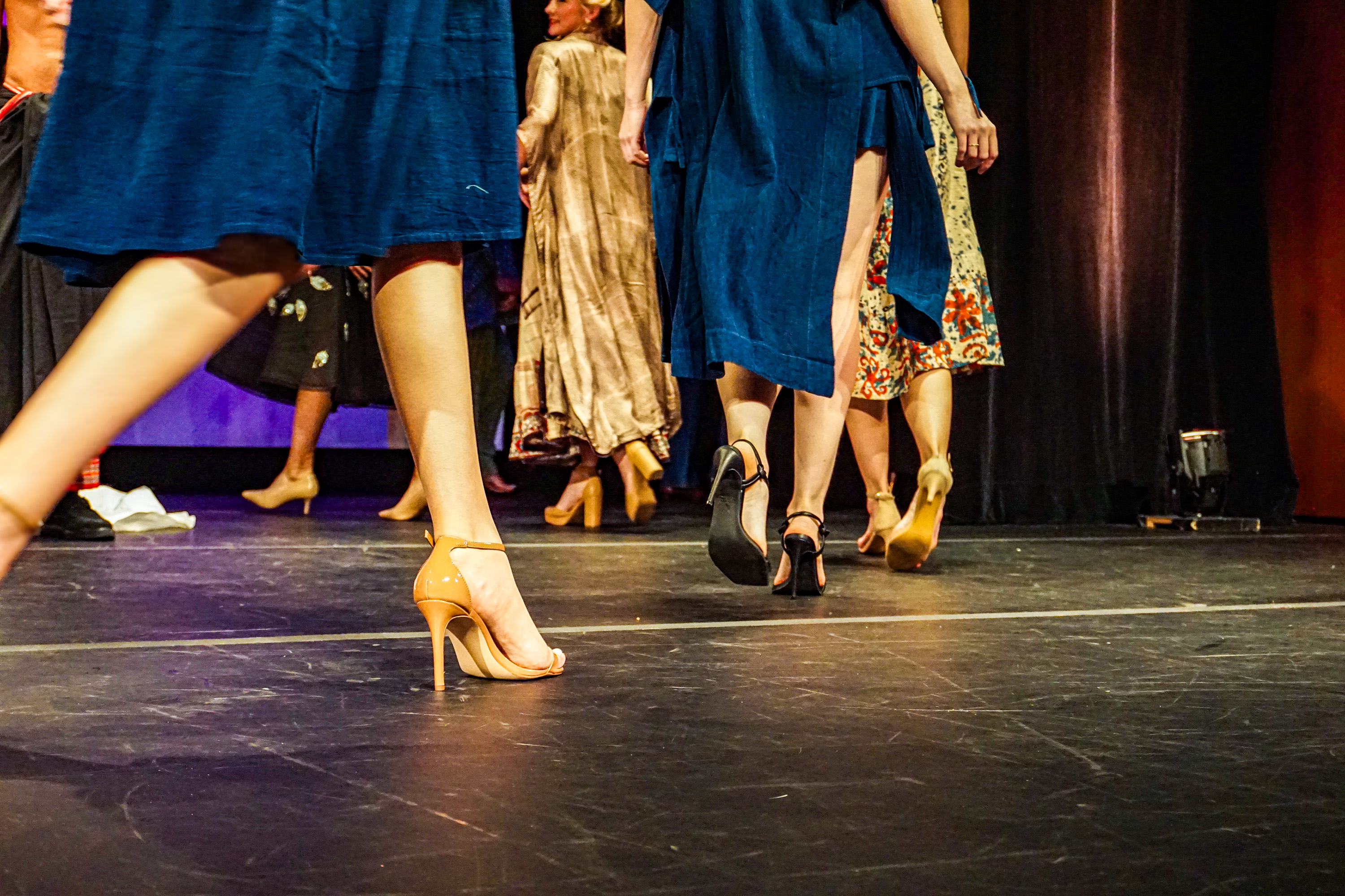 a low shot image on a runway of models shoes as they walk around the stage