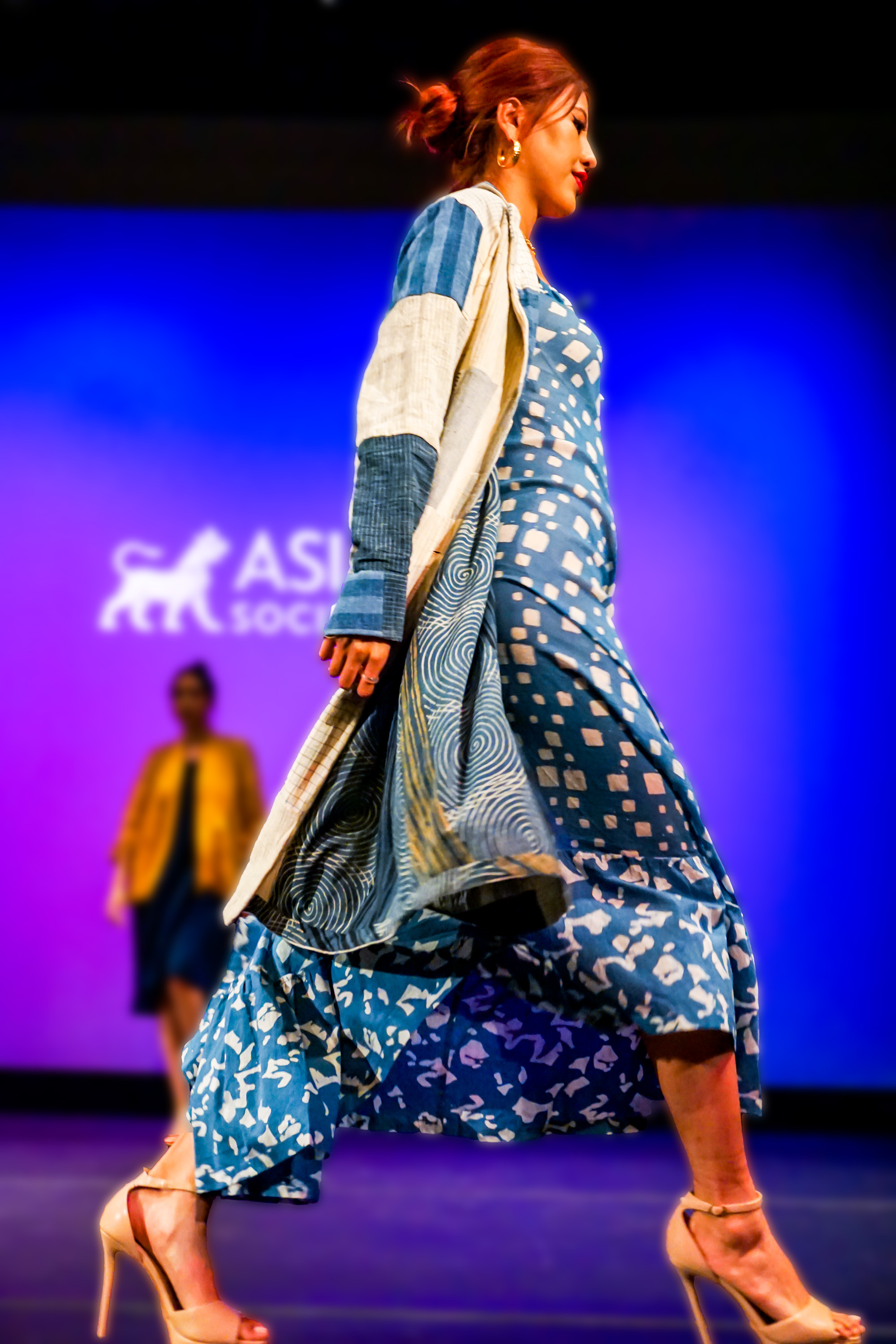 female model in blue Indian style dress and high heel shoes walking off runway stage