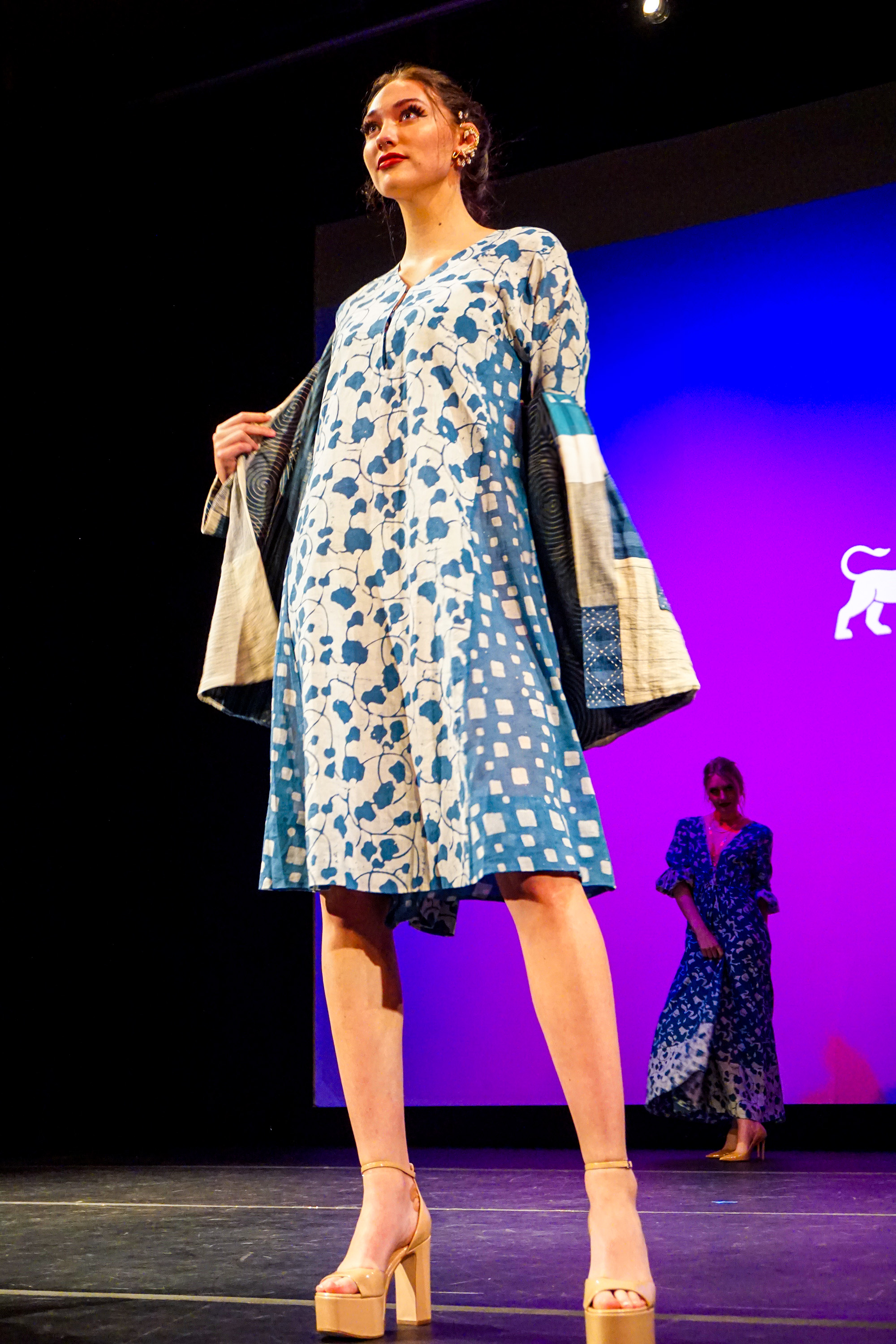 Female model in blue dress posing for the crowd on the runway