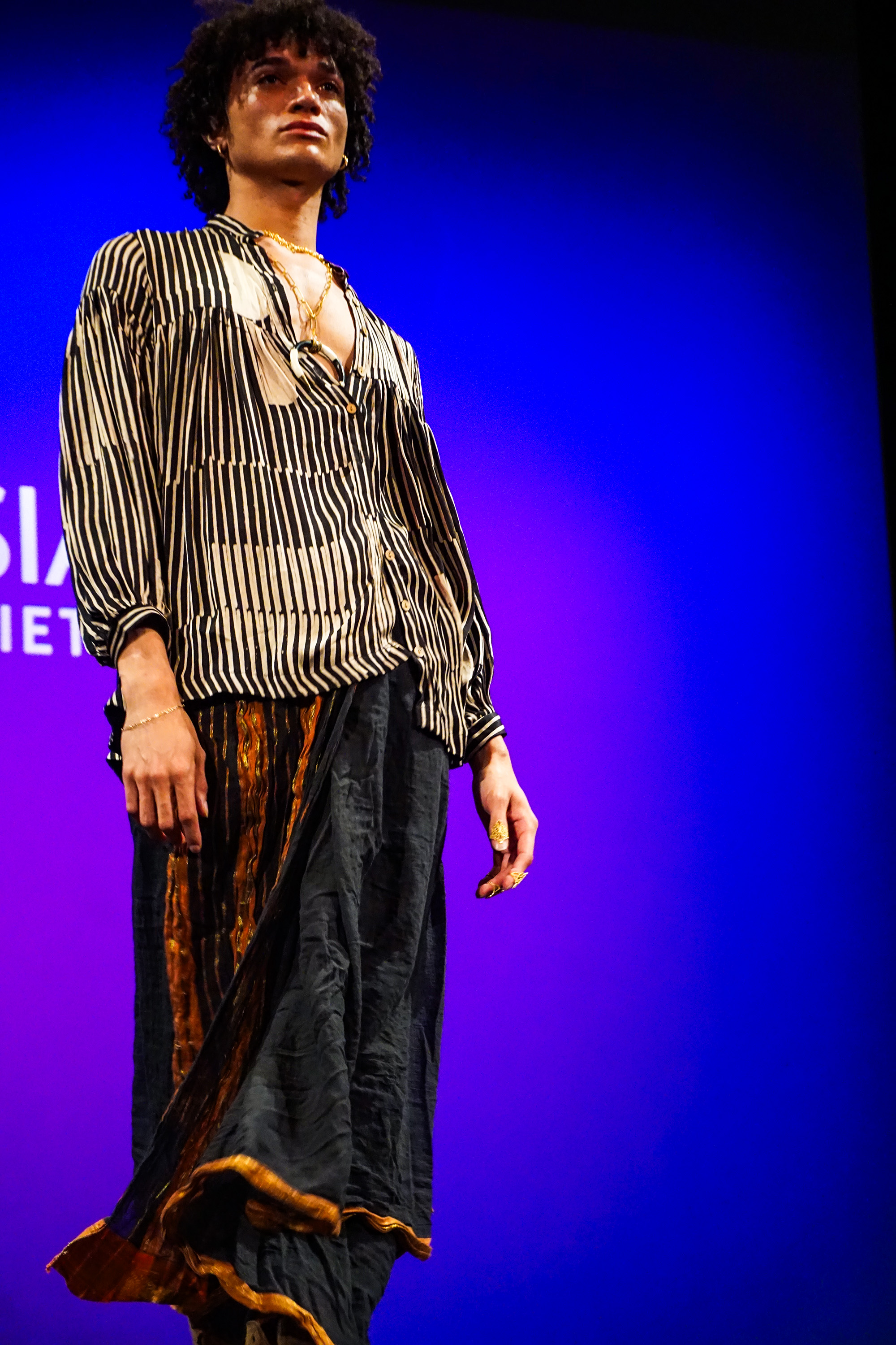 A male model adorned in Indian style attire posing at the runway confidently