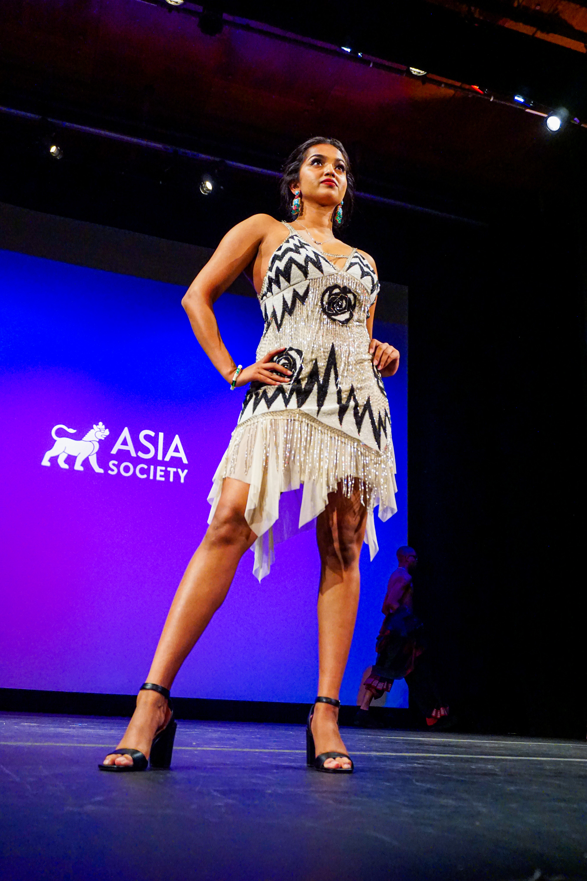 a female model standing confidently hand on hips posing at the end of a runway