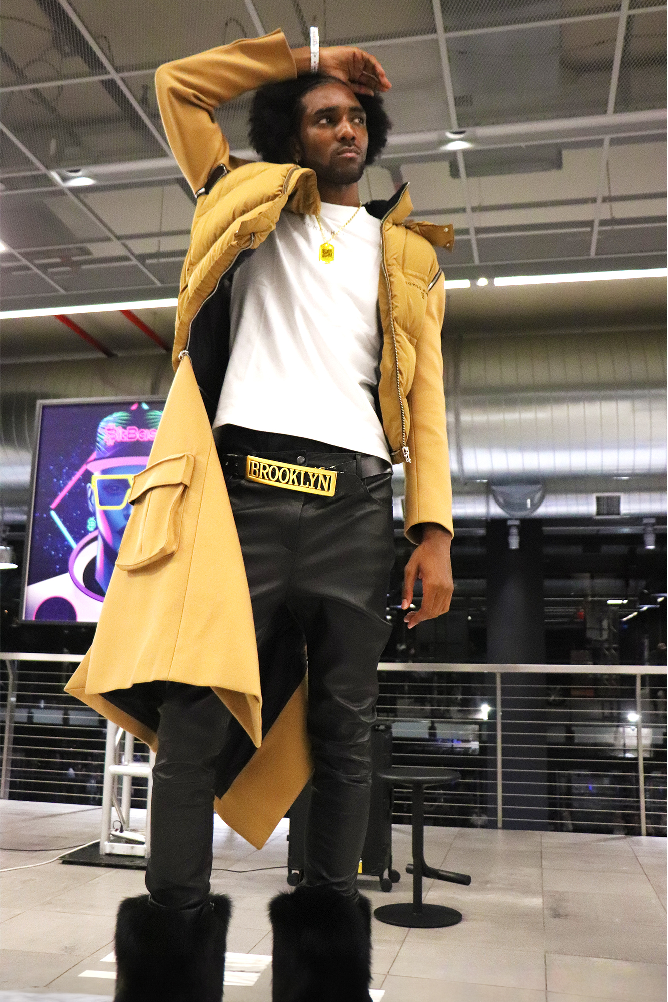 a model wearing Romeo Hunte's fashion clothing at a fashion show including a jacket and "Romeo" belt buckle