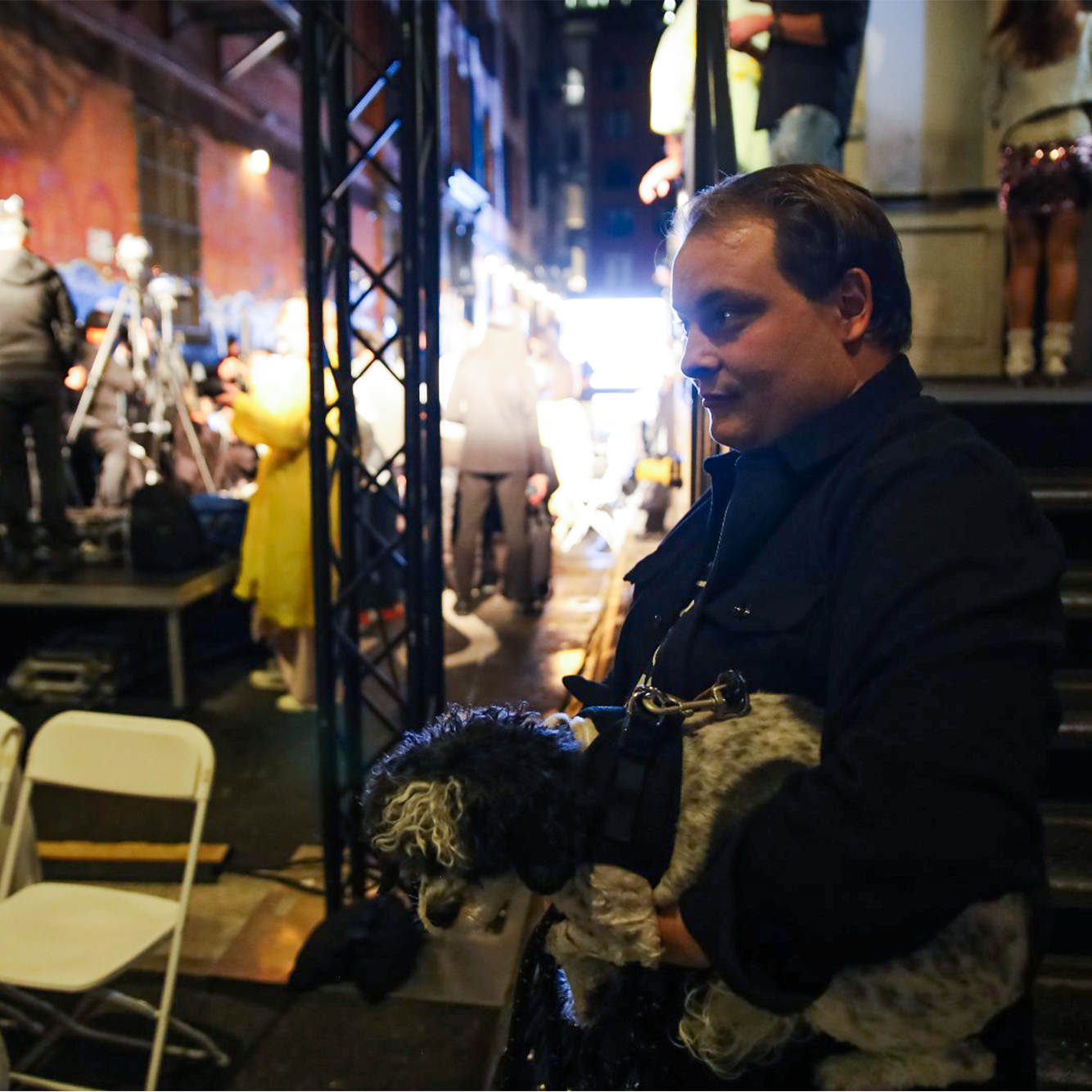 Artist Ryan Prizzi Zwick holding his dog in front of the fashion runway outdoors at Walker Hotel New York