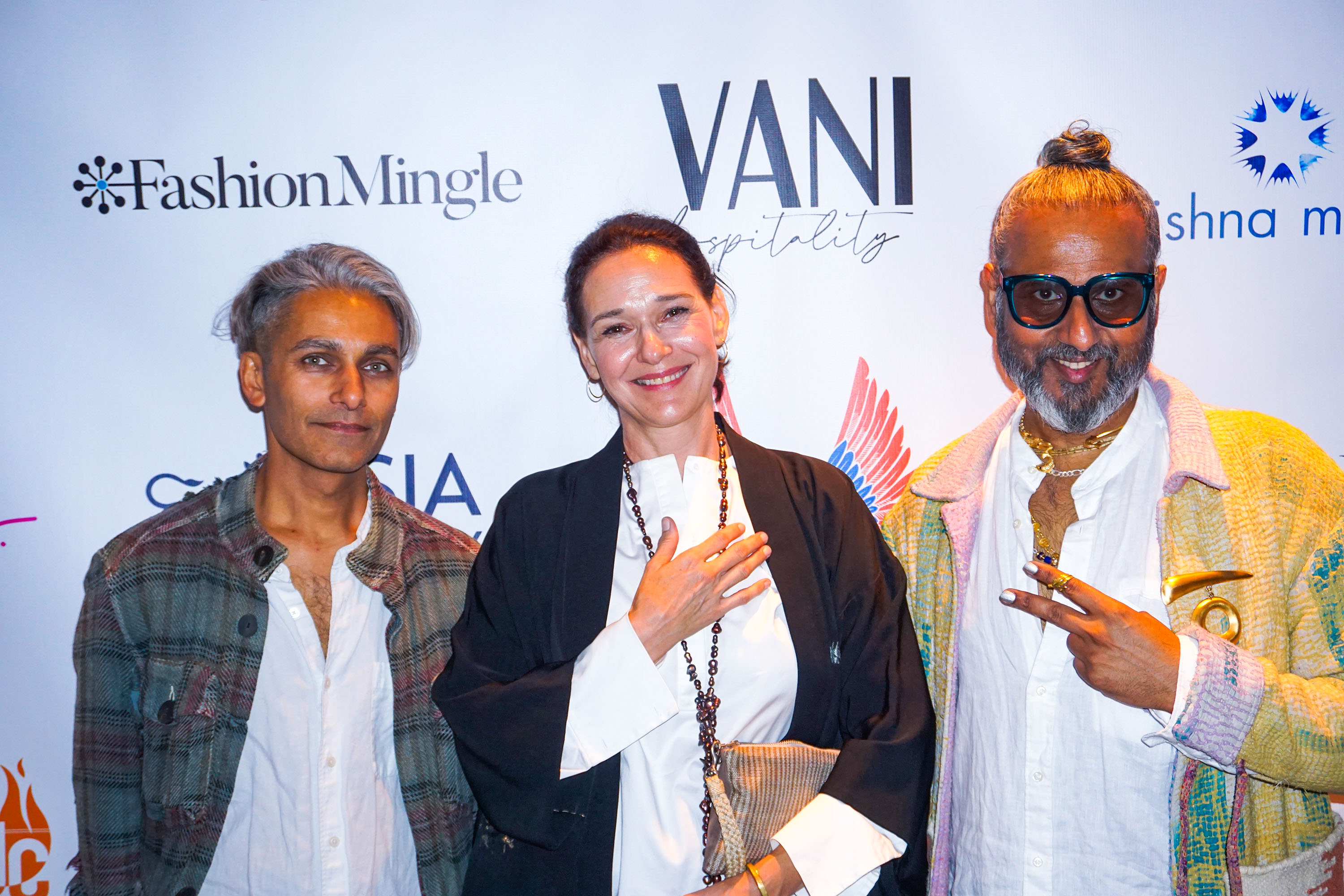 ajay shrivastav, Sandy Dalal and Carmen Artigas standing in front of a step and repeat banner