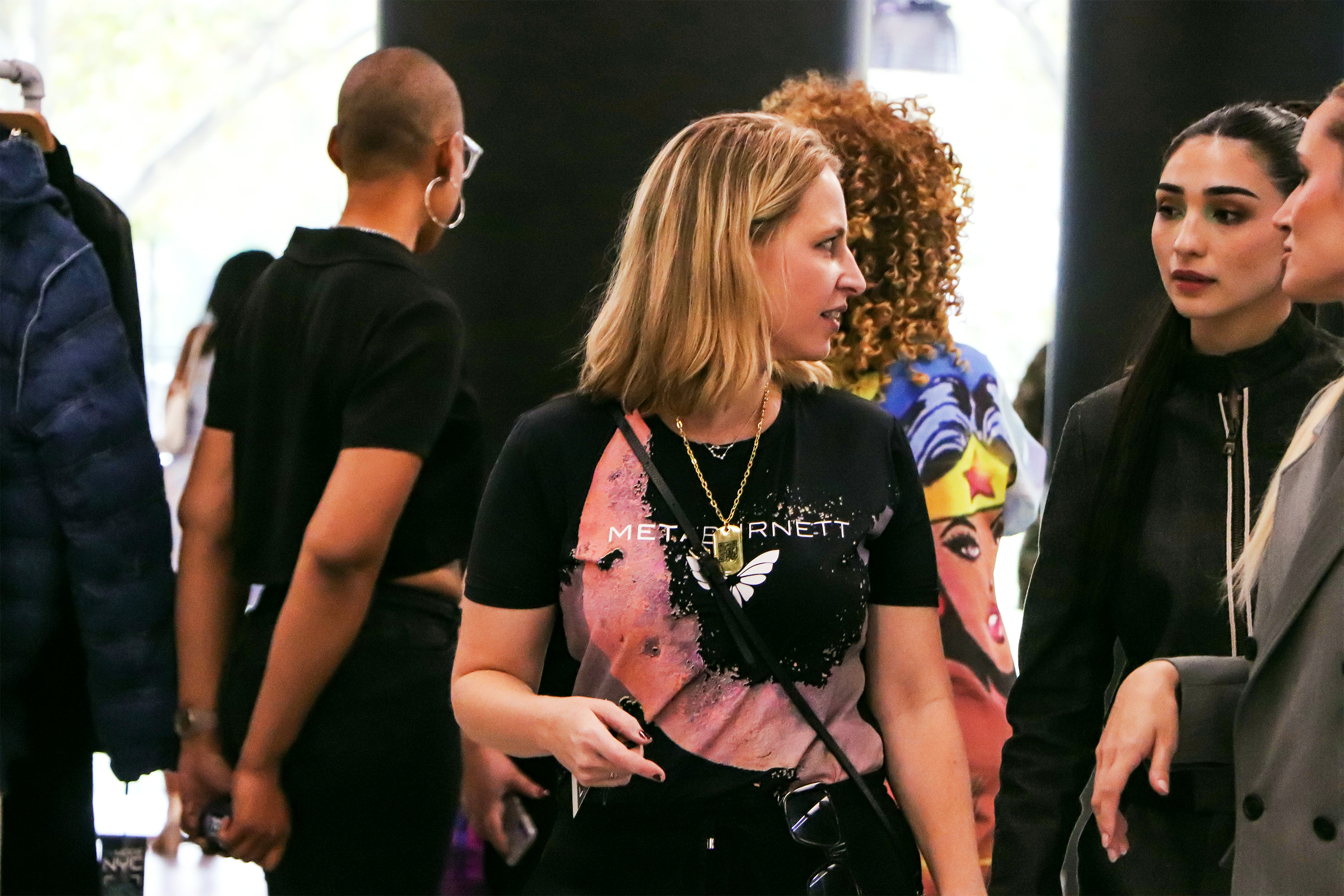 Emily Burnett backstage at DeMODE interacting with staff for the fashion show while wearing a jumptag dog tag necklace