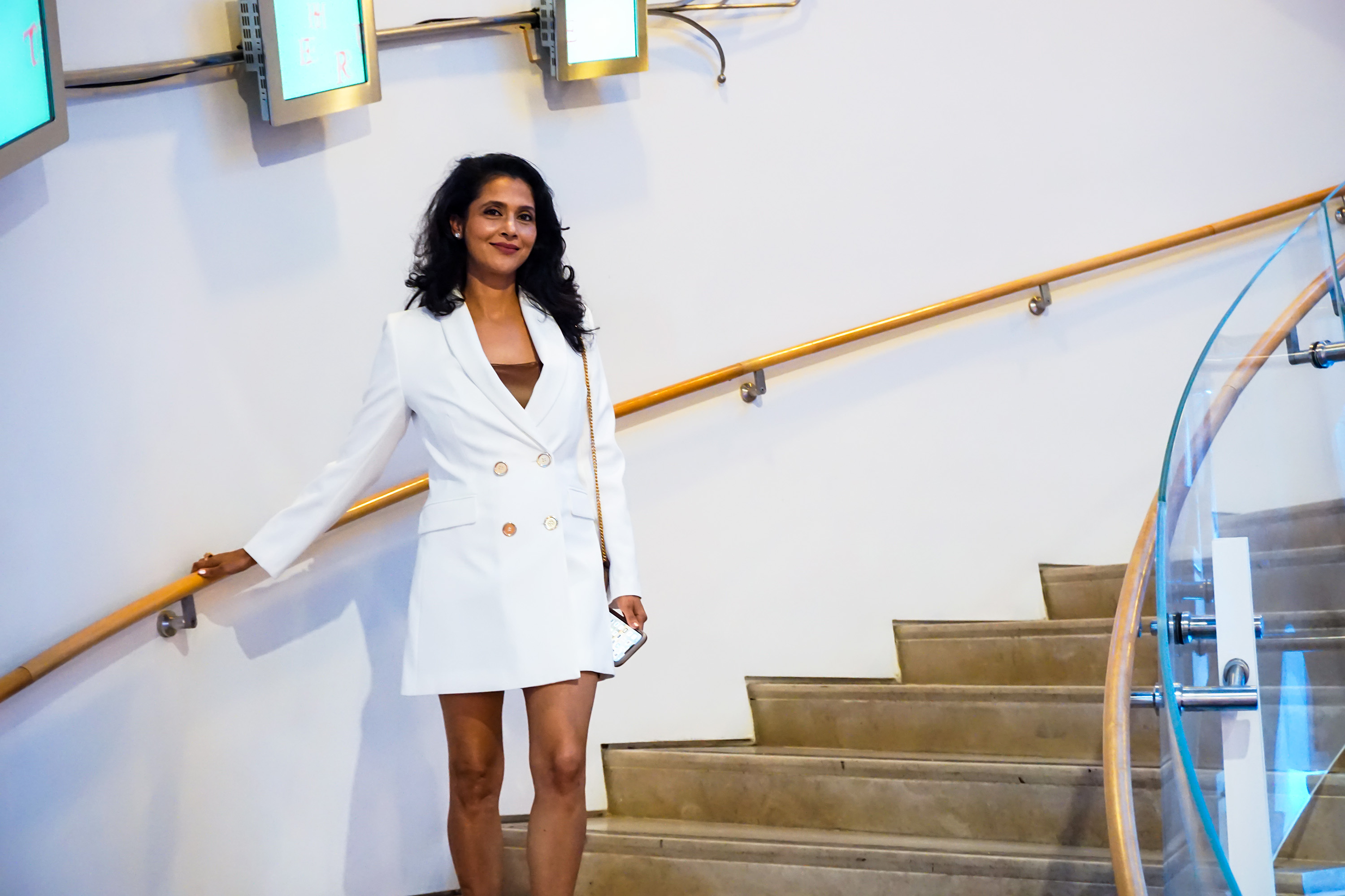 a fashionable woman posing along a spiraled staircase