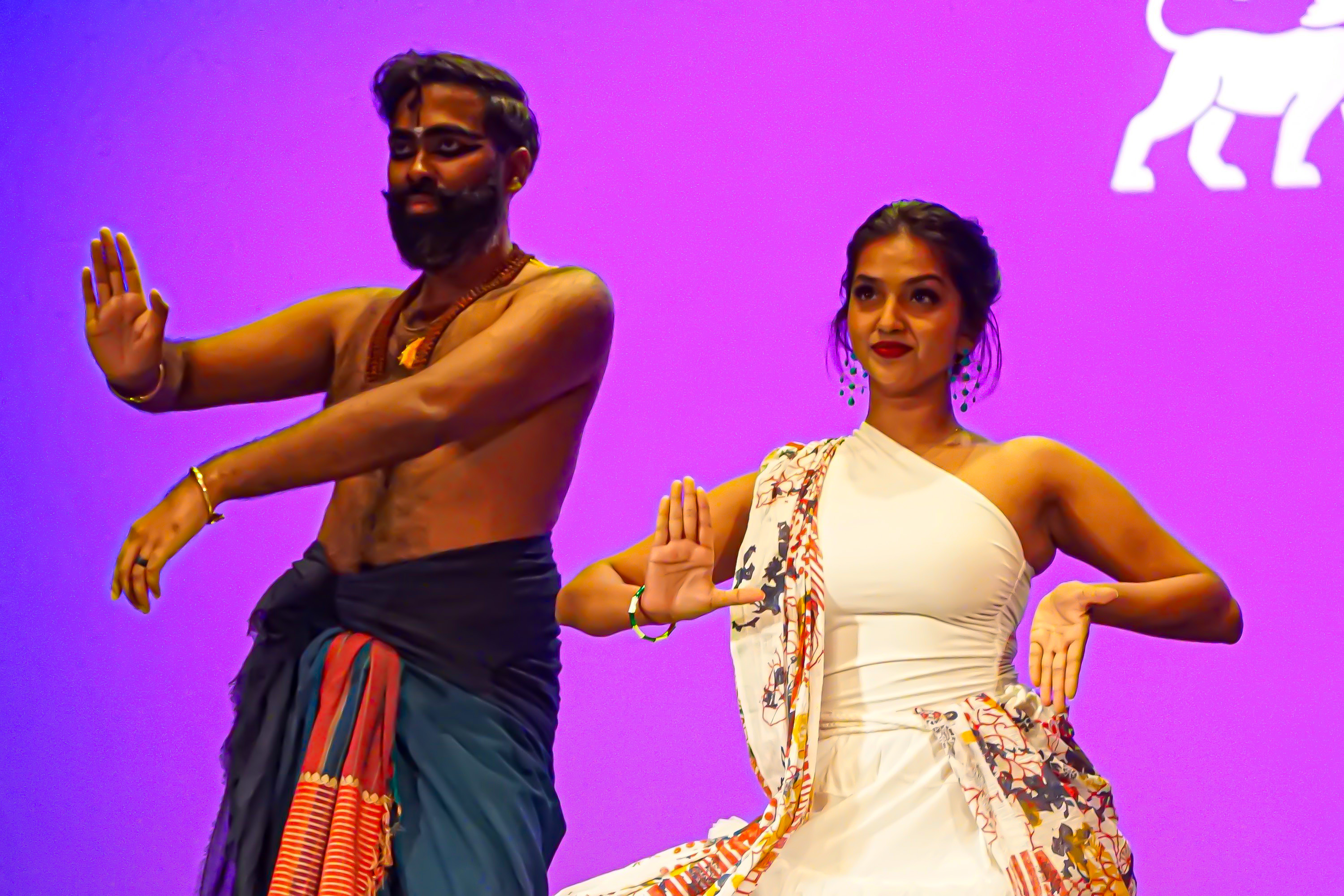 Jeeno Joseph and female model wearing Indian textiles and dancing against a purple background on stage