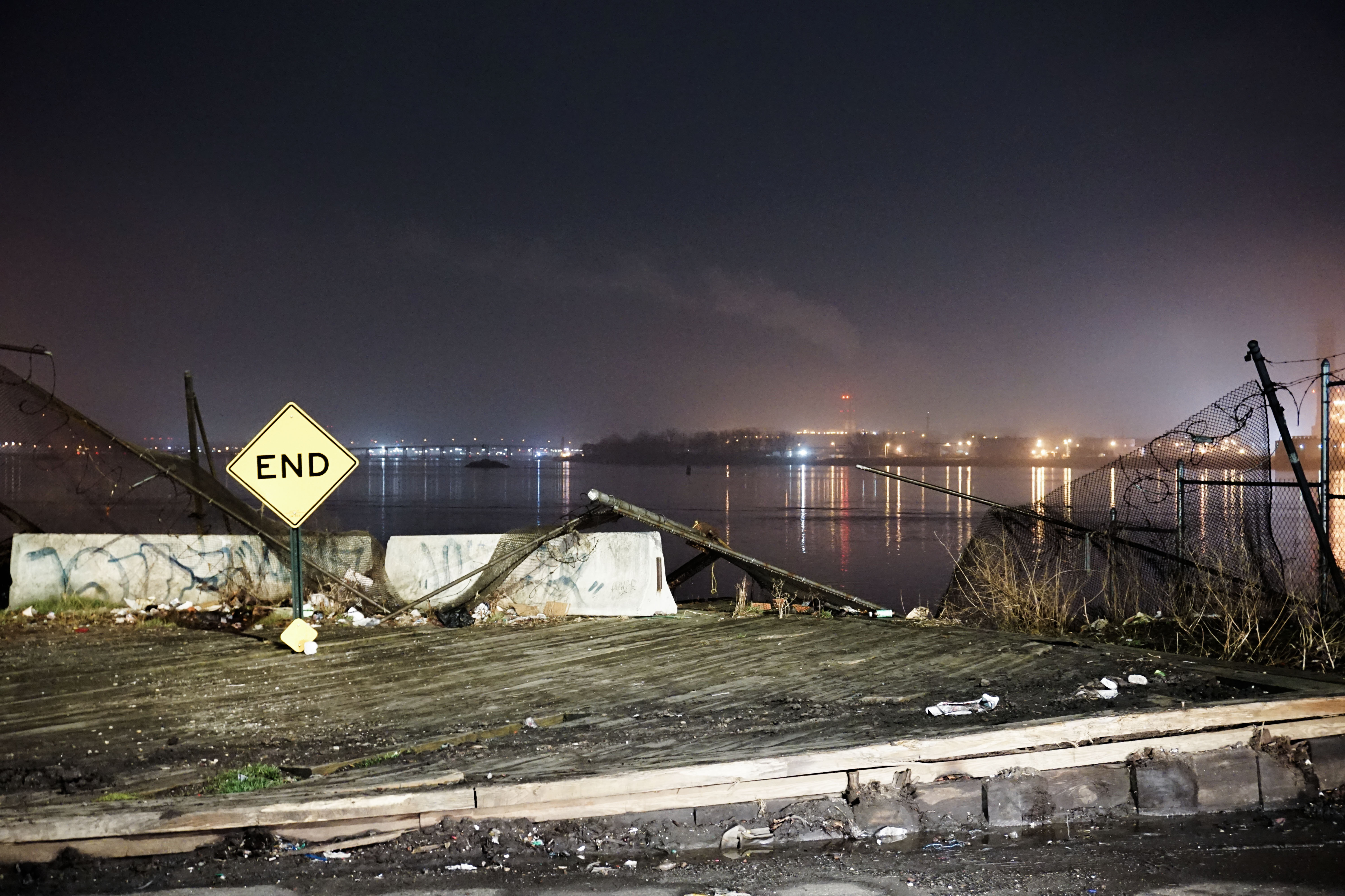 an industrial background with a sign that says end and a river behind it at night time