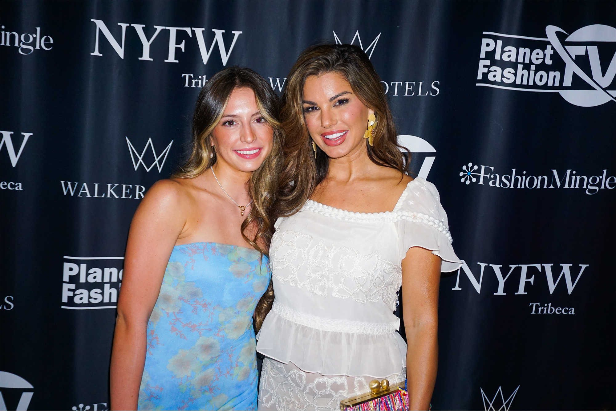 Victoria Vesce and friend smiling in front of step and repeat banner at Walker Hotel fashion show